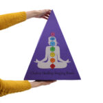Pyramid shaped 7 chakra singing bowl gift set being held in two hands, showing full colour printed design and size of gift box.