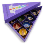 Pyramid shaped 7 chakra singing bowl gift set with printed lid opened, showing bowls and sticks within.