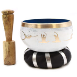 Small 10.7cm white painted brass yoga moves singing bowl stood on cushion next to puja stick.